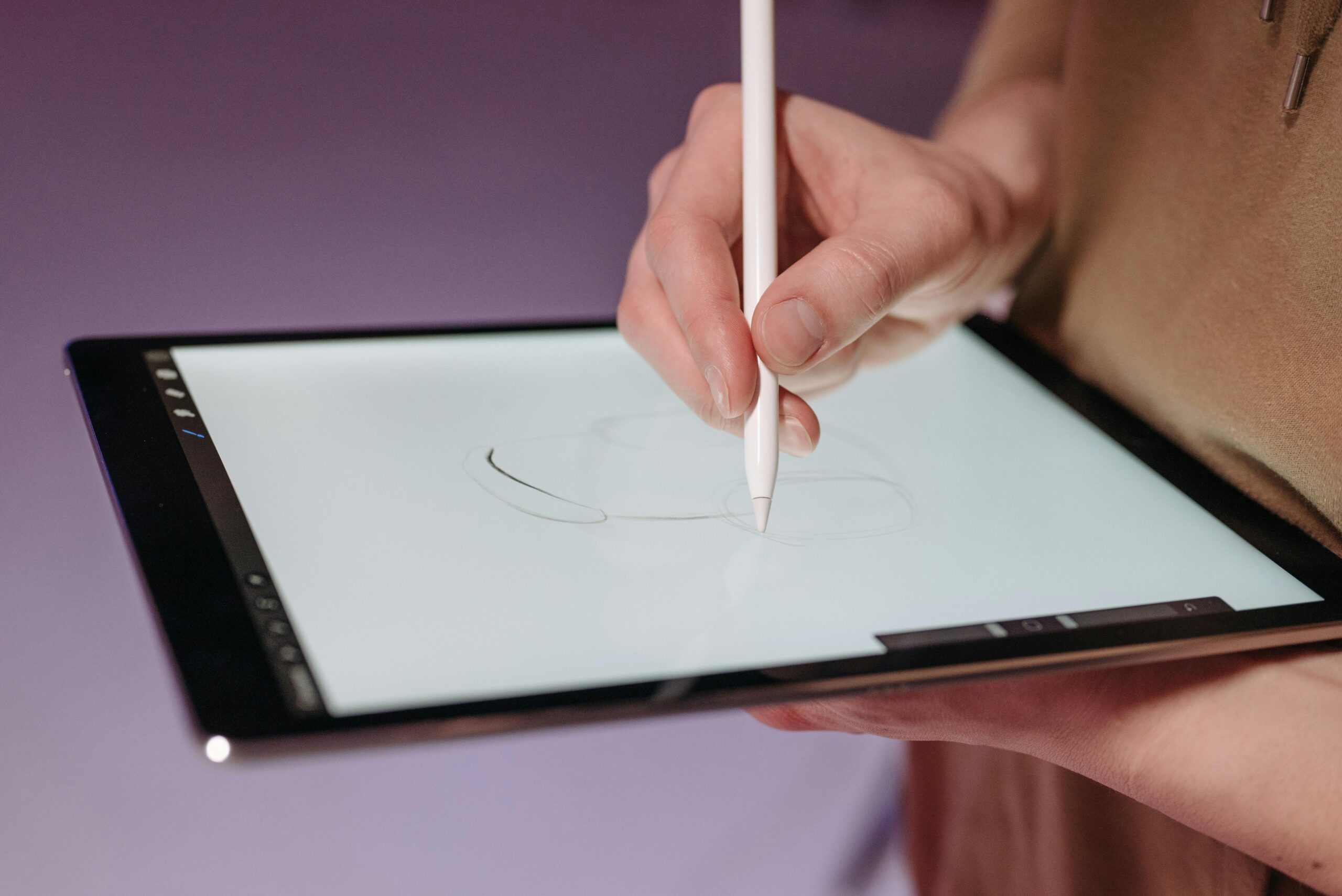 Hand using stylus pen on a tablet for sketching, showcasing modern digital design tools.